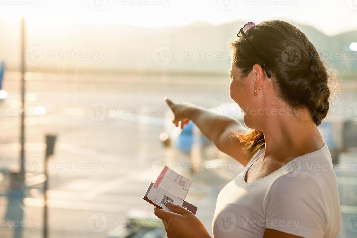 beautiful brunette showing a plane at the airport photo