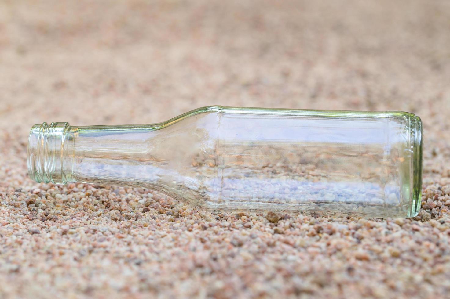 Empty glass bottle in the sand photo