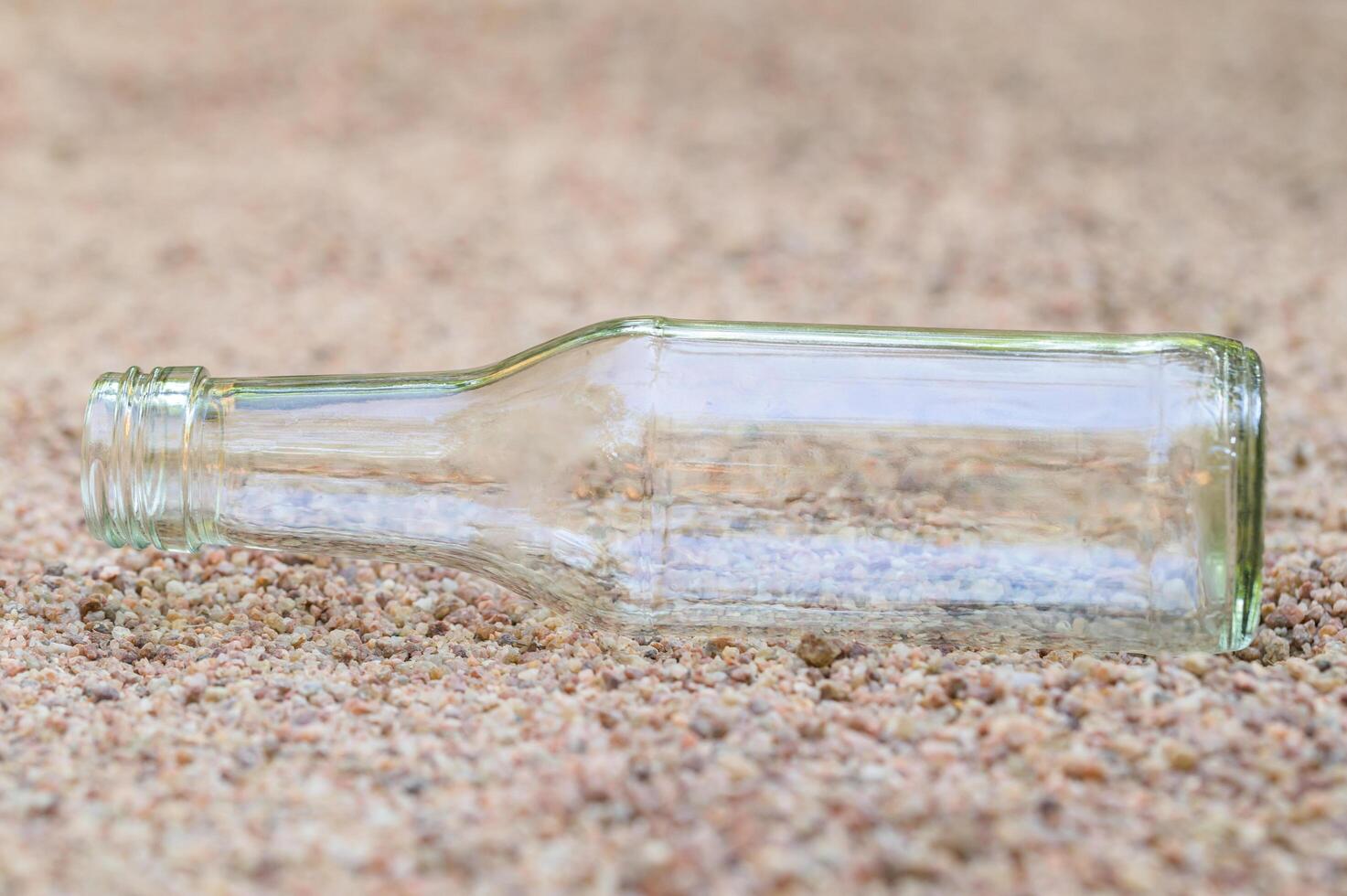 botella de vidrio vacía en la arena foto