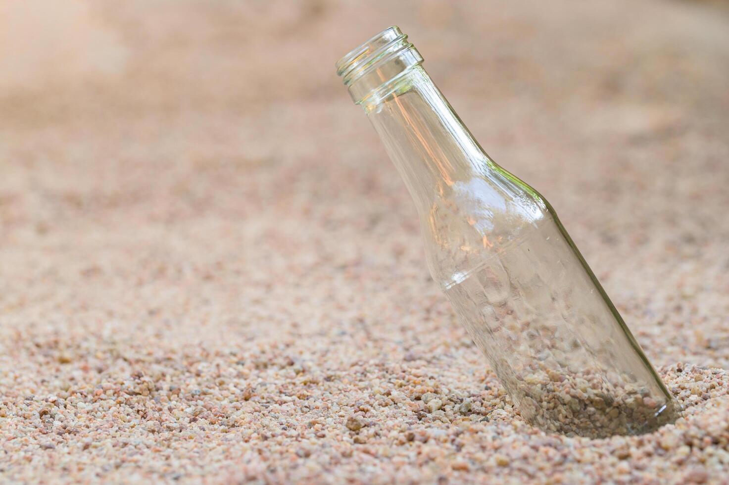 Empty glass bottle in the sand photo