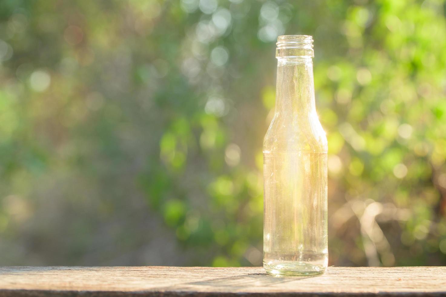 una botella de vidrio brillando sobre un piso de madera foto