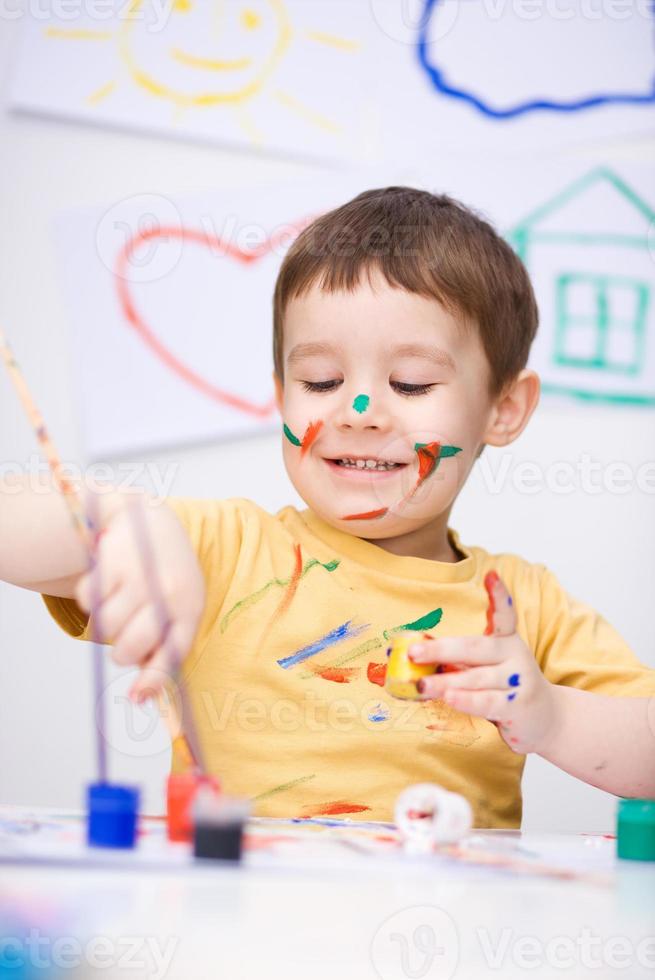 Portrait of a cute boy playing with paints photo