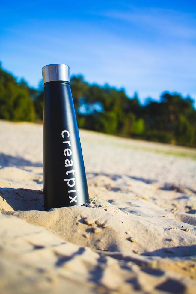 Netherlands, 2020 - Black water bottle in sand photo