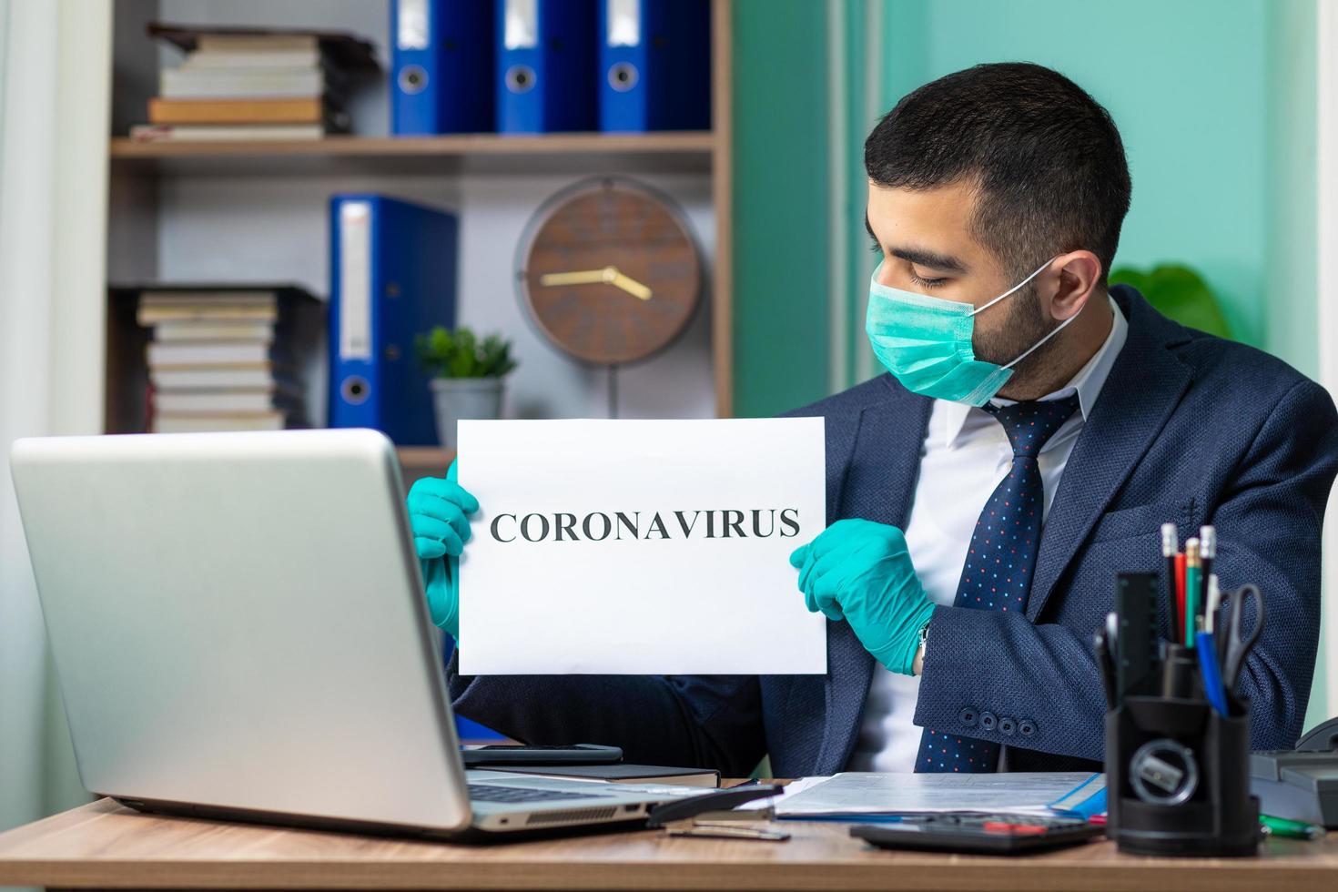 joven empresario con cartel de coronavirus foto