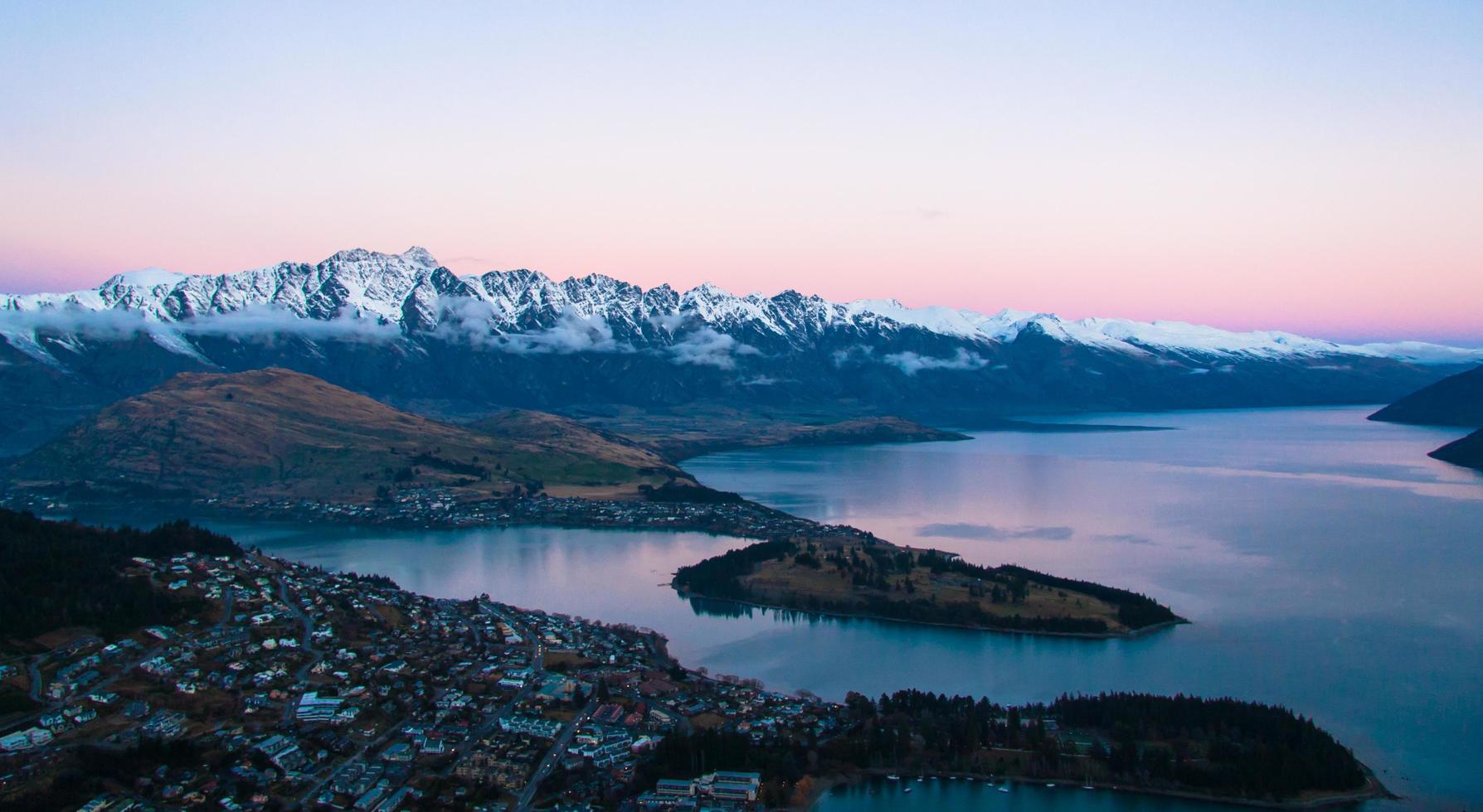 Body of water with city and mountains at sunset photo