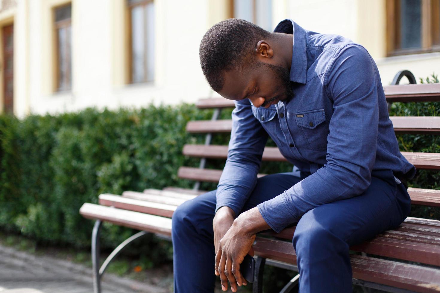 Tired man sits on the bench outside photo