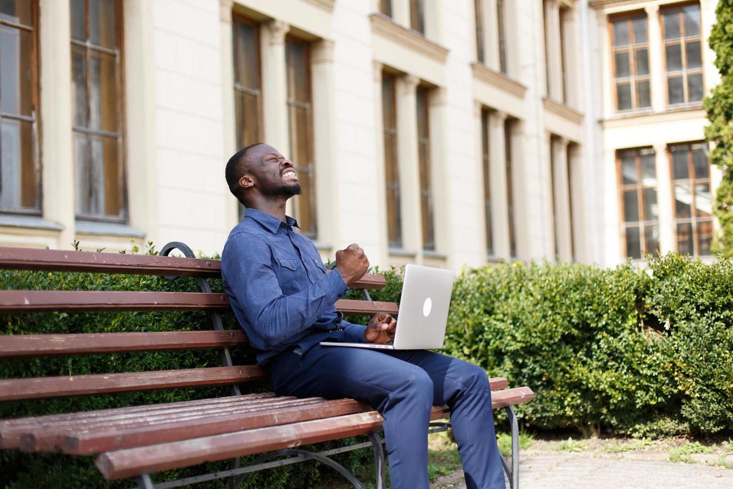 Man celebrating outside with laptop photo