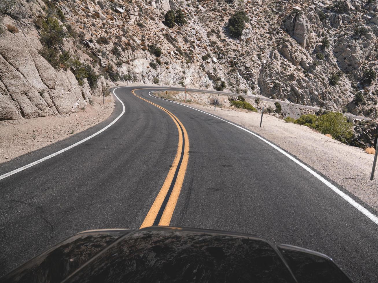 Black asphalt road near gray rocky mountain during daytime photo