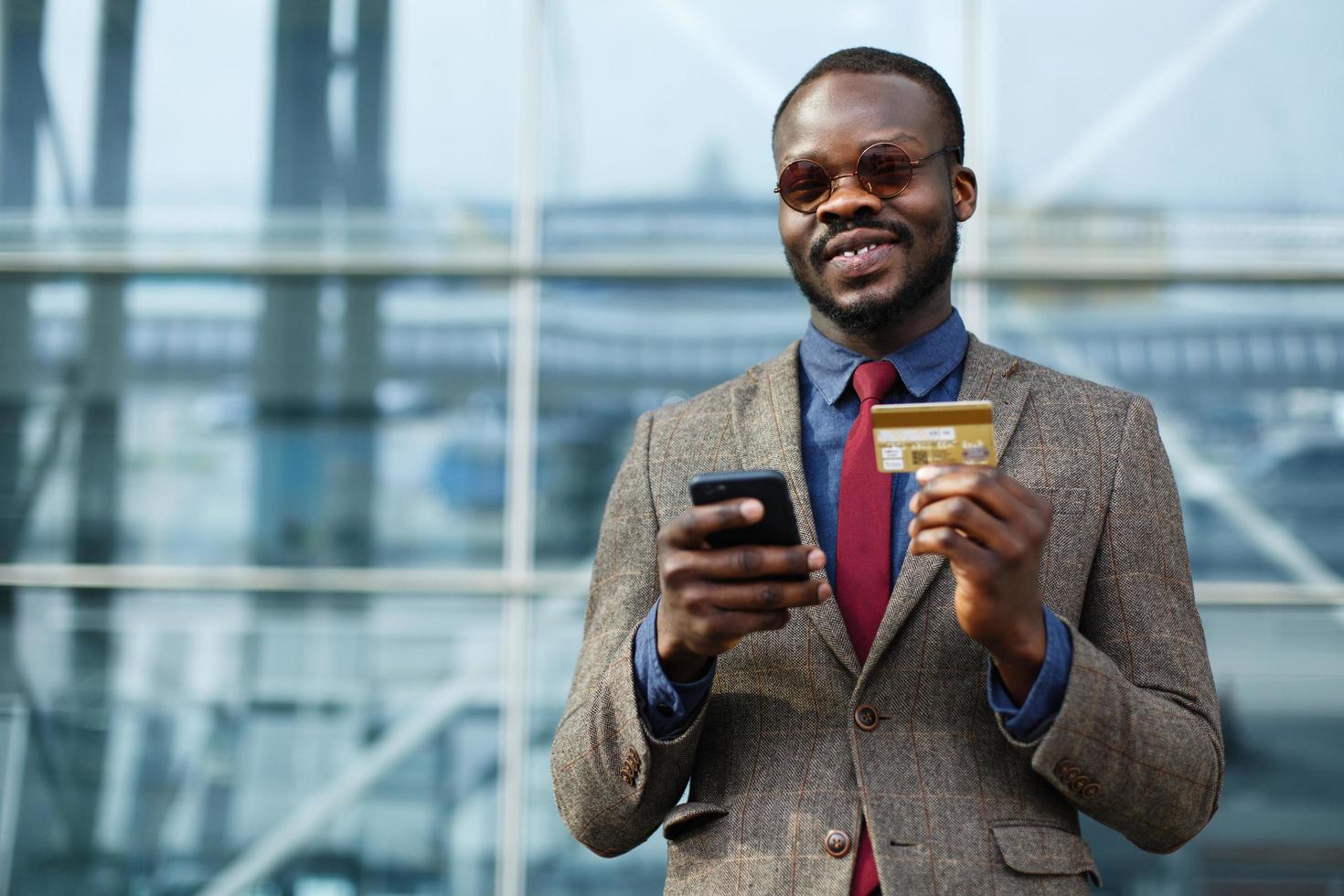 Stylish African American businessman types information from his credit card photo