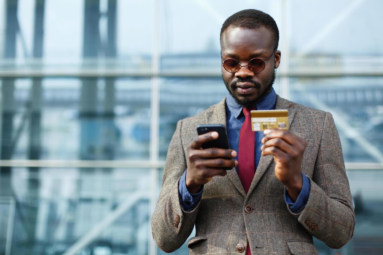 Stylish black businessman typing information from his credit card photo