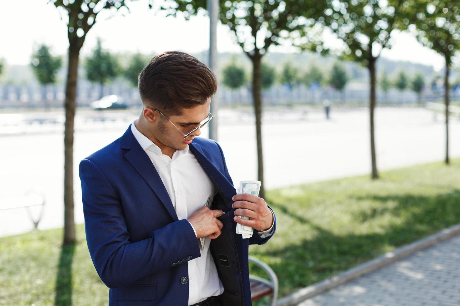 hombre en traje de negocios pone dinero en efectivo en su bolsillo interior foto