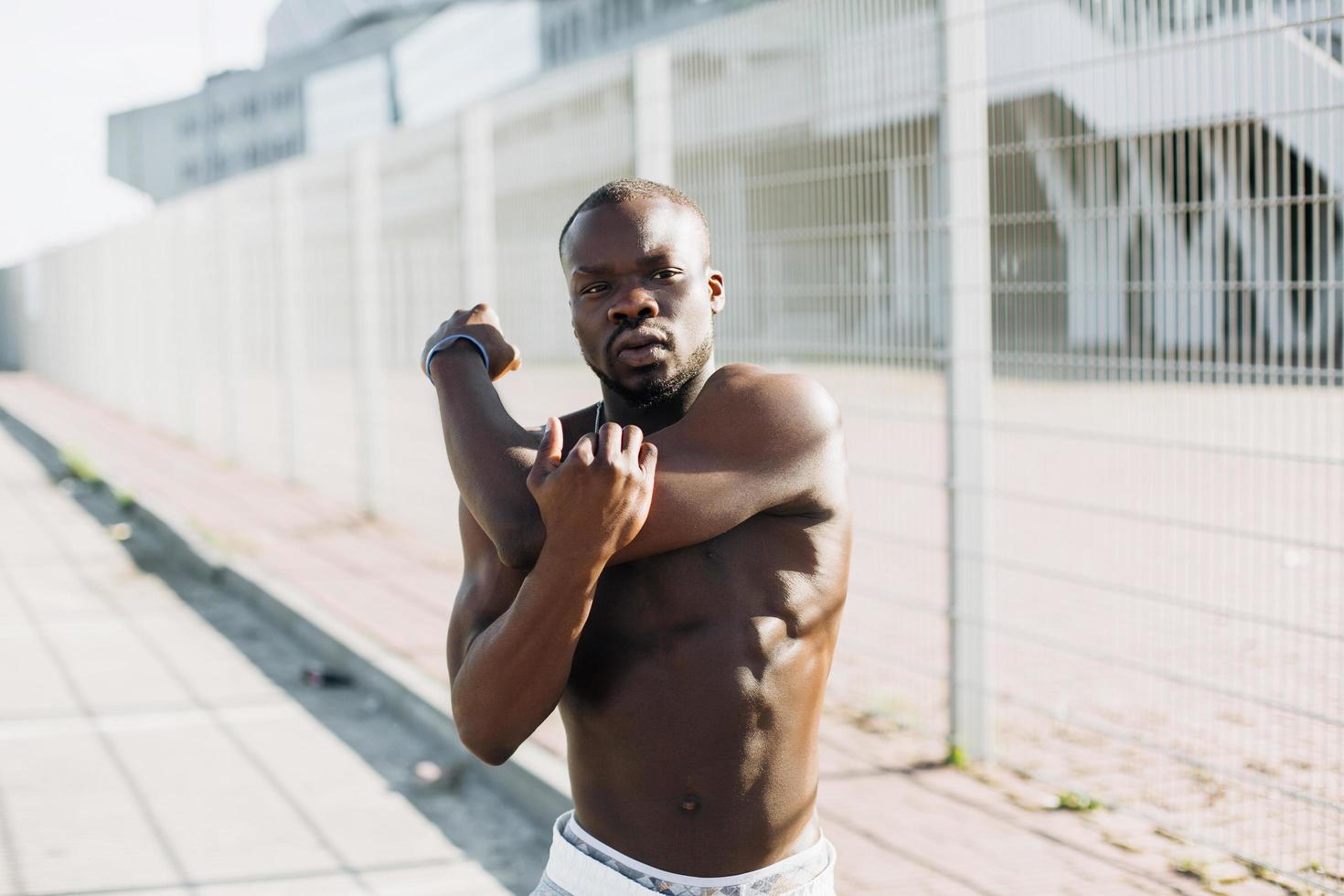 Apuesto hombre afroamericano hace estiramientos antes de un ejercicio exterior foto