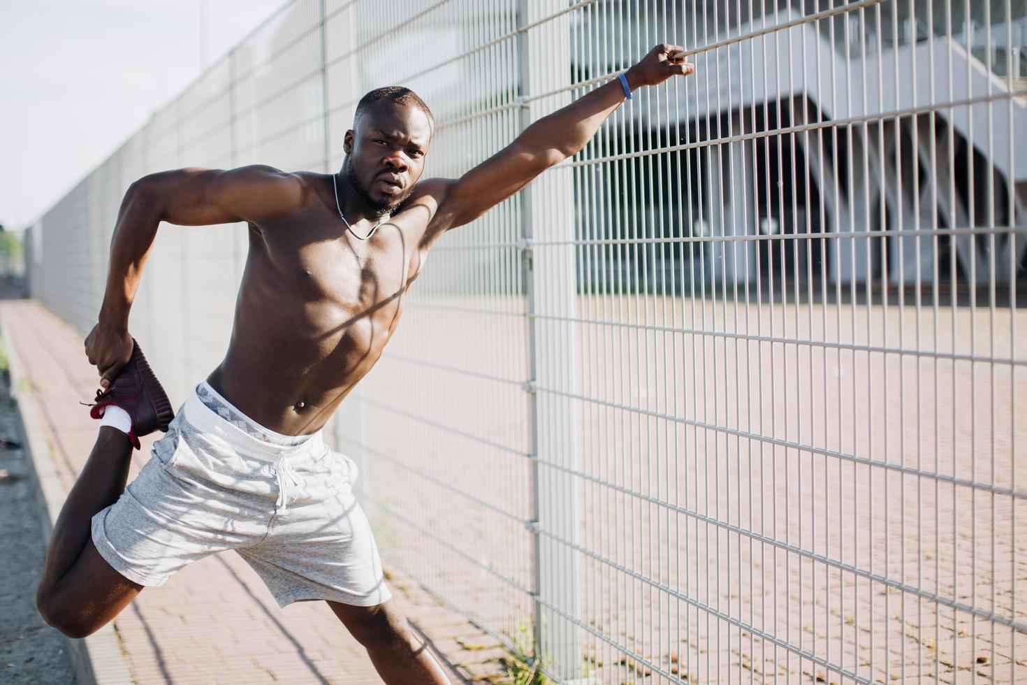 Apuesto hombre afroamericano hace estiramientos antes de un ejercicio exterior foto