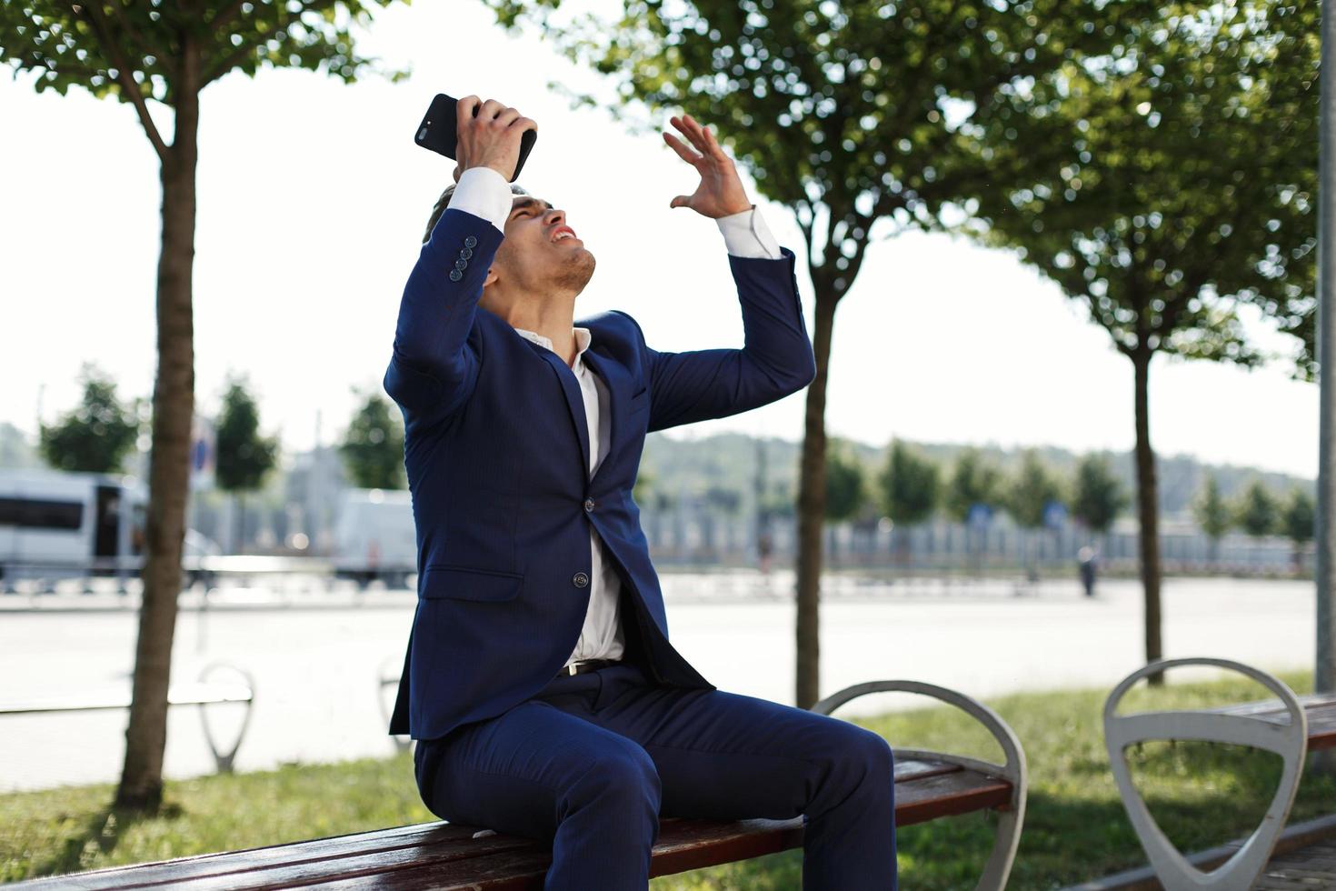 Feliz joven empresario tiene smartphone en su brazo y grita foto