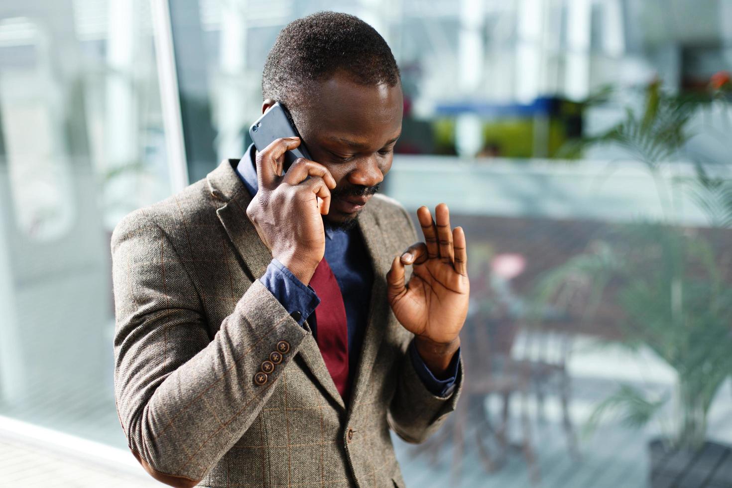 Elegante empresario afroamericano habla en su smartphone foto