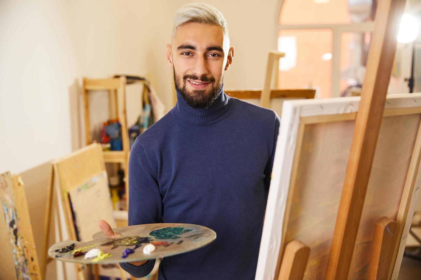 Man draws a painting with oils and smiles photo