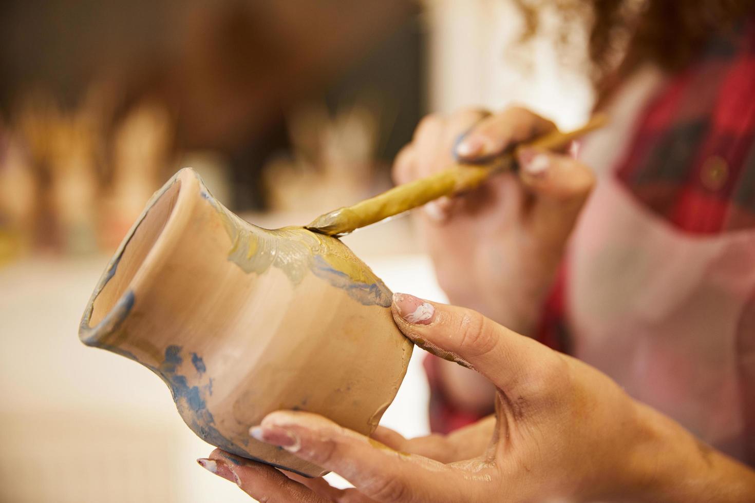 Close up, girl paints a vase before baking photo