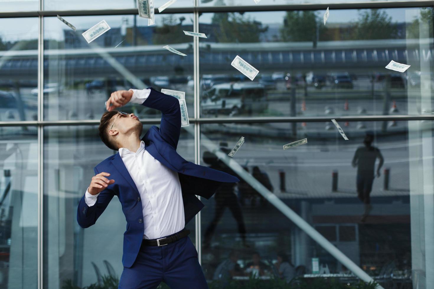 Dollars fly around handsome young businessman photo