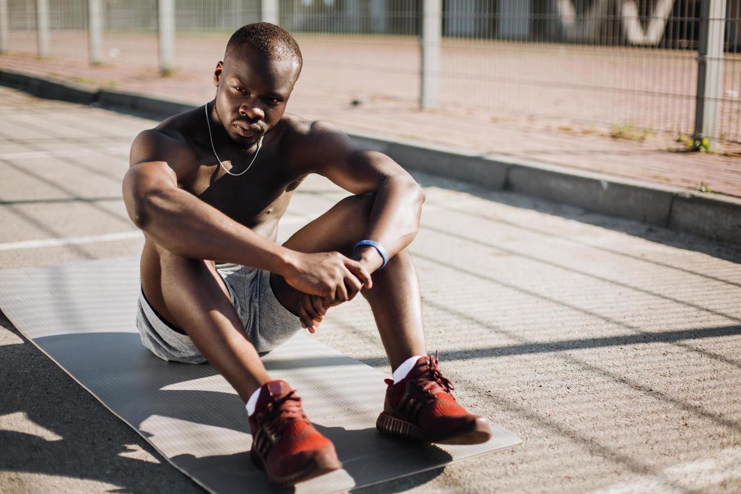 African American man sits tired on the ground after doing his exercises photo