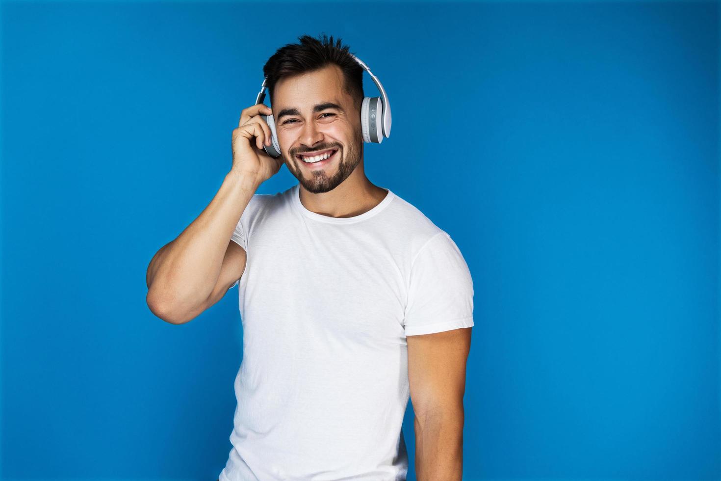 Cute man smiles and listens to something in the headphones photo