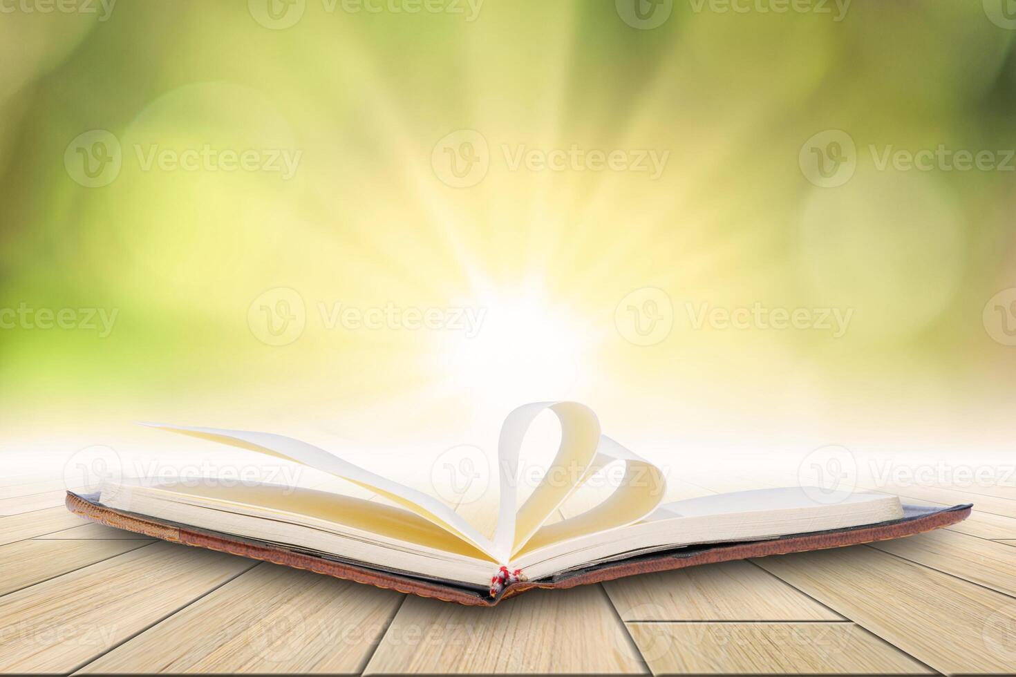 An open book on a wooden table with sunlight shining through the window photo