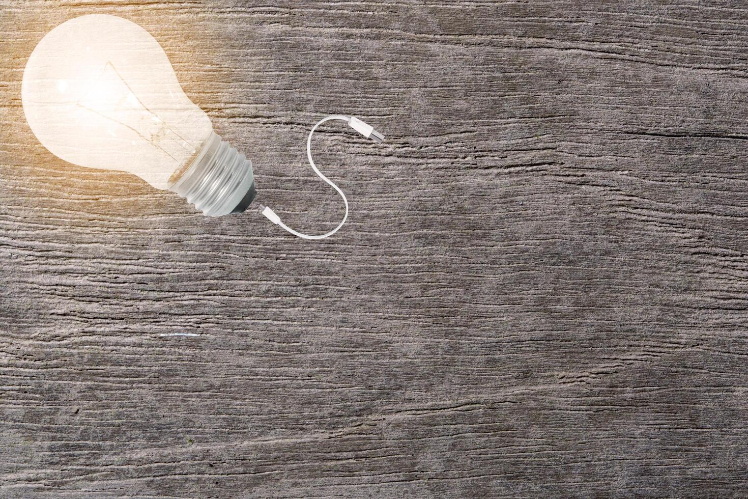 Light bulb and cable on wooden background photo