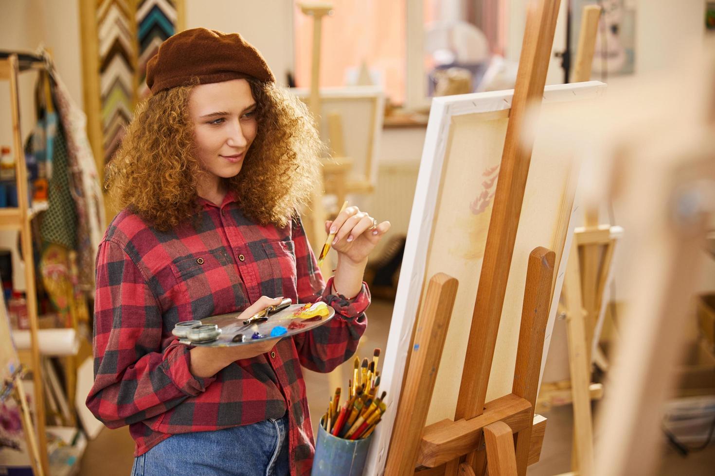 Young girl holds a palette with oil paints and a brush photo