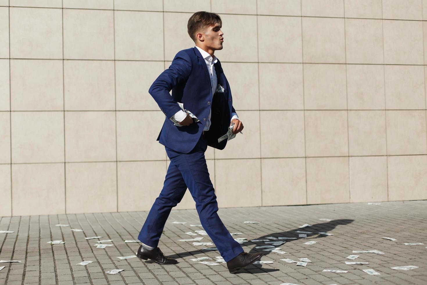 joven empresario caminando a través de billetes de un dólar en la calle foto