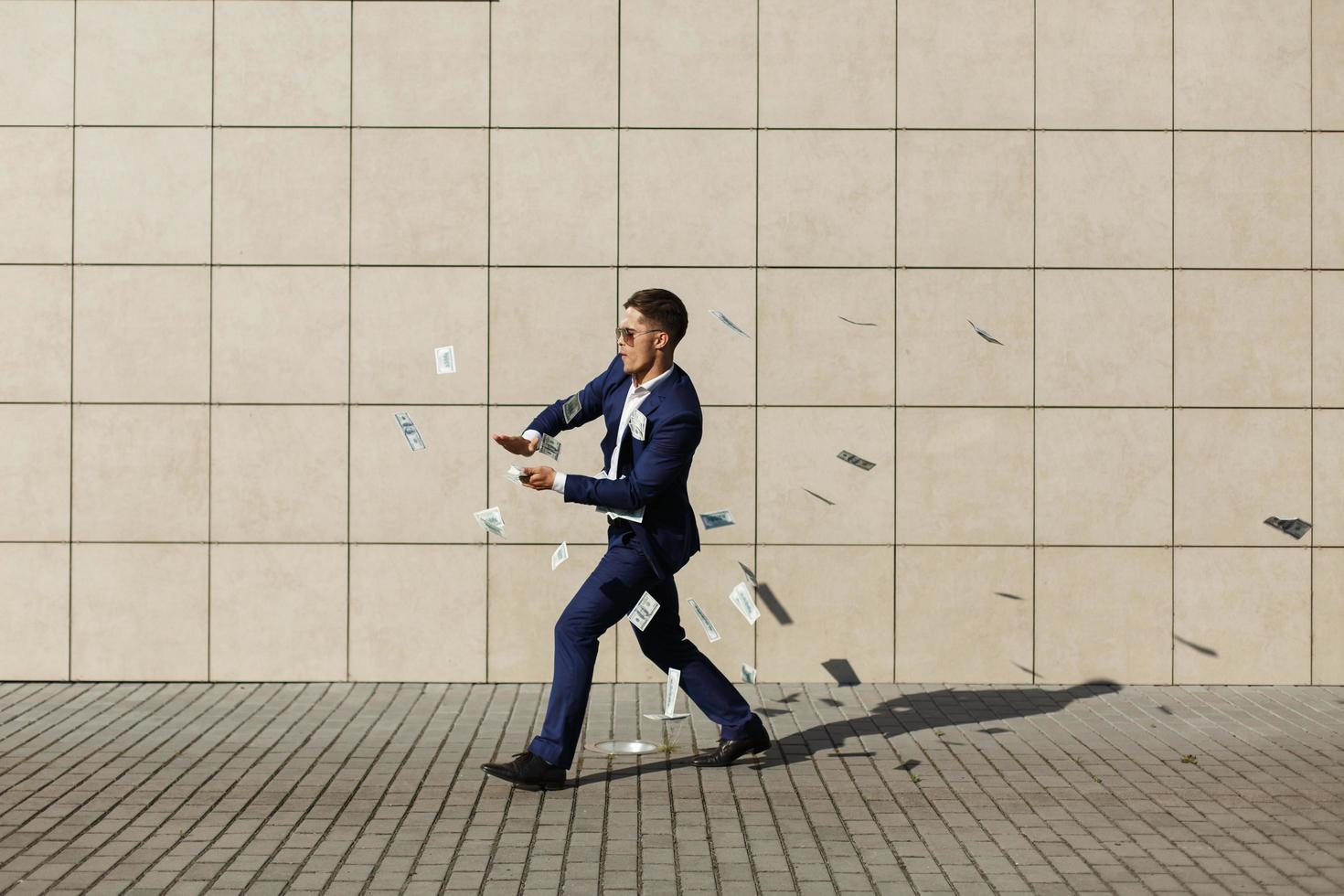 Young businessman throws around dollars and dances on the street photo