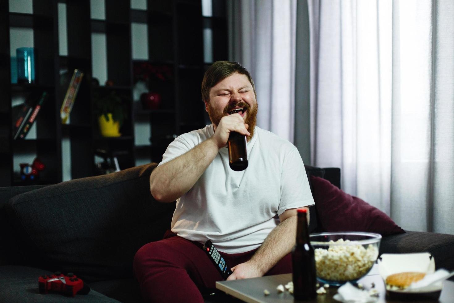 Fat man drinks beer on the sofa photo