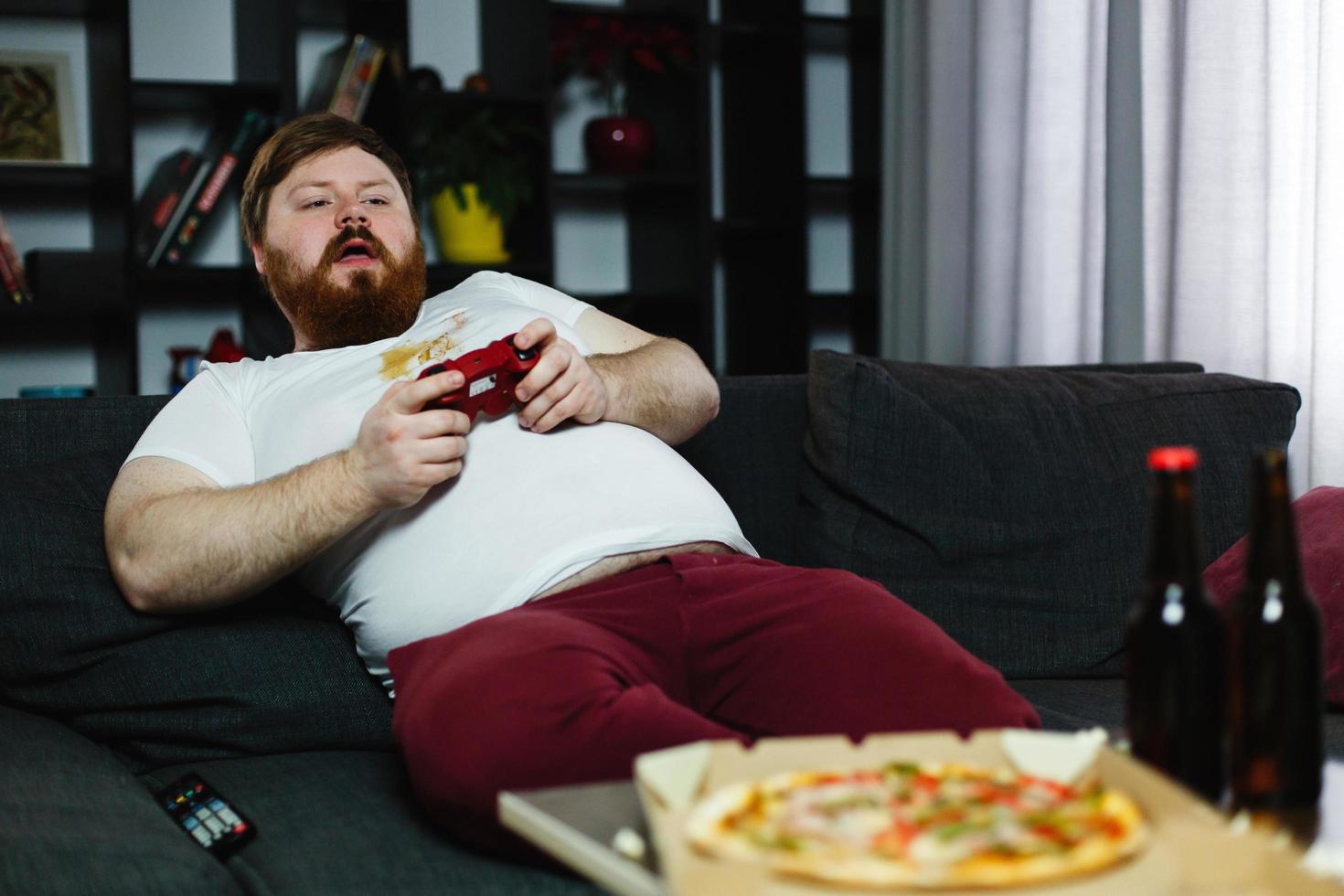 Happy fat man in dirty shirt plays video games photo