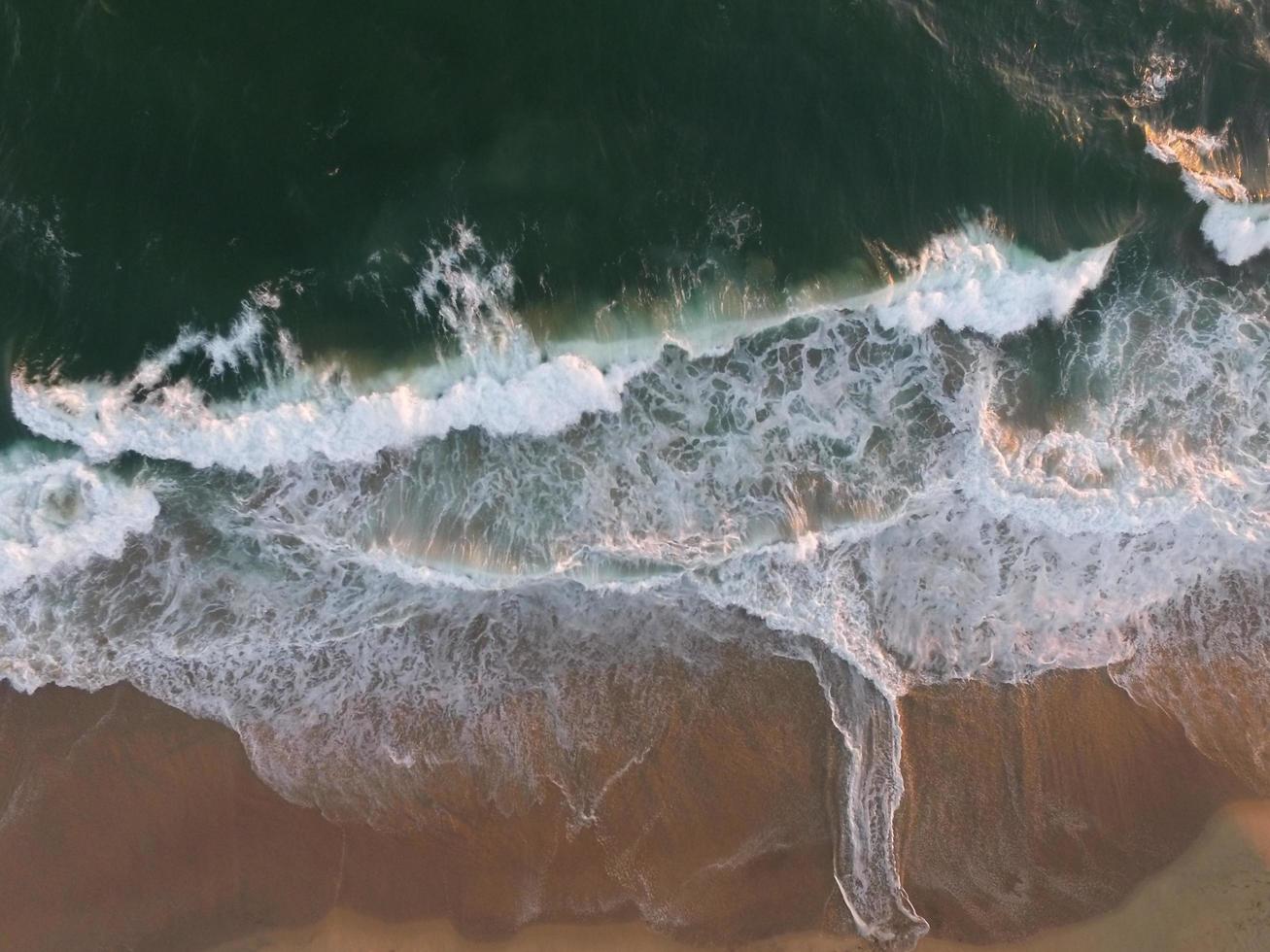 Sunlit body of water splashing on the shore photo