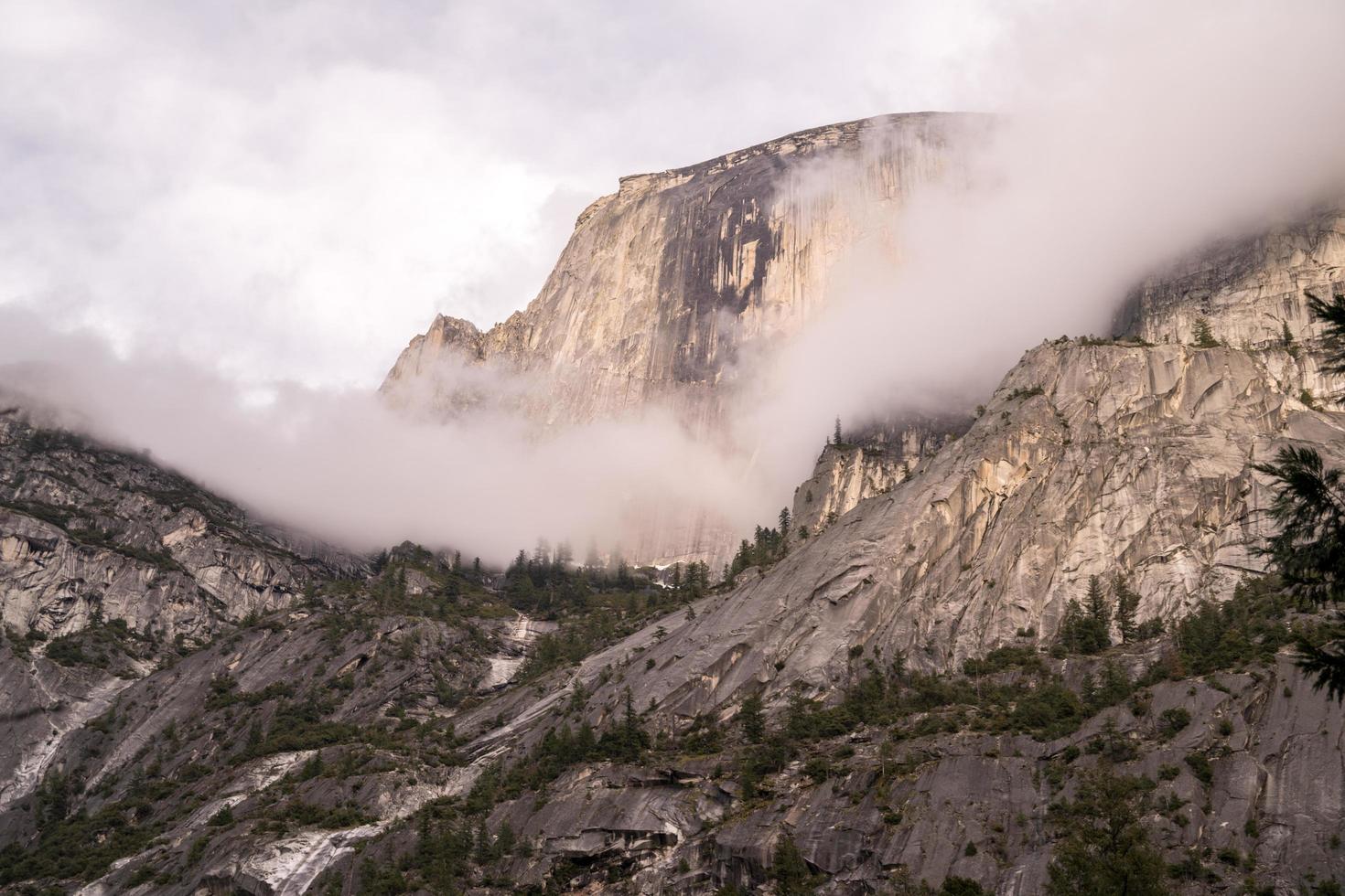 montaña cubierta de nubes y rodeada de árboles foto