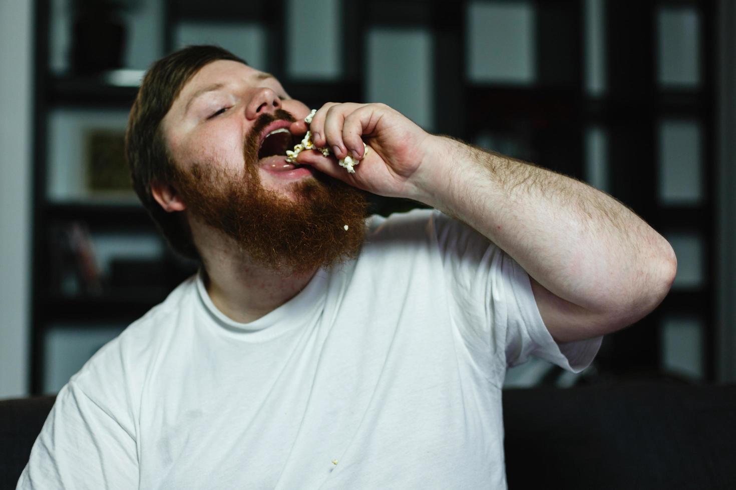 Primer plano de un hombre gordo mientras come palomitas de maíz foto