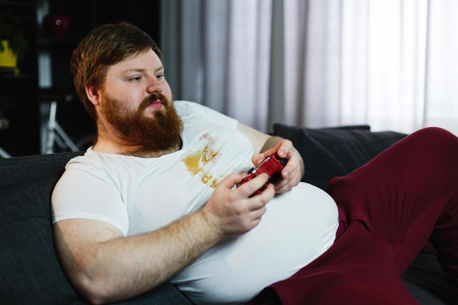 Happy fat man in dirty shirt plays video games photo