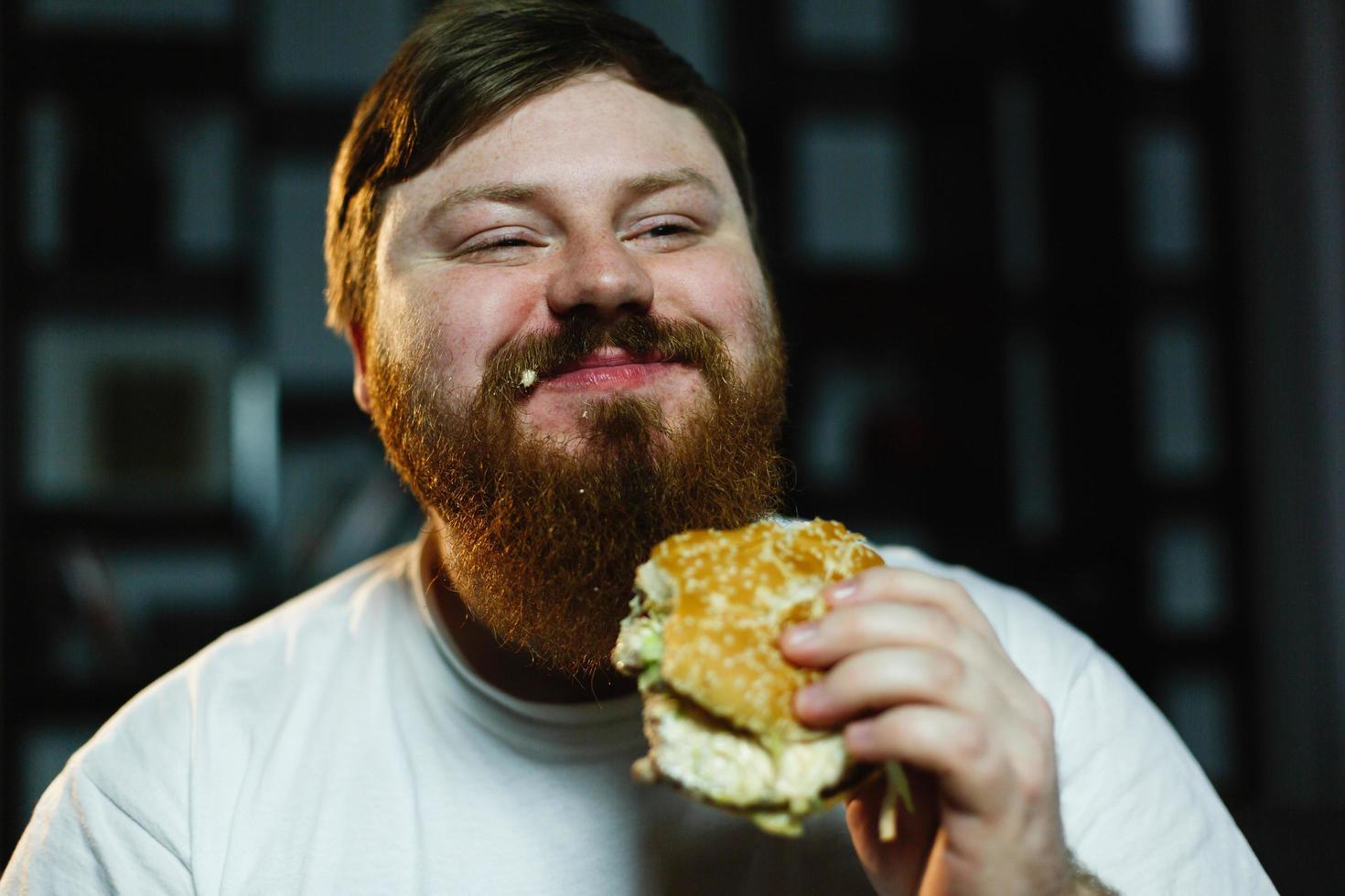 hombre gordo sonriente come hamburguesa foto