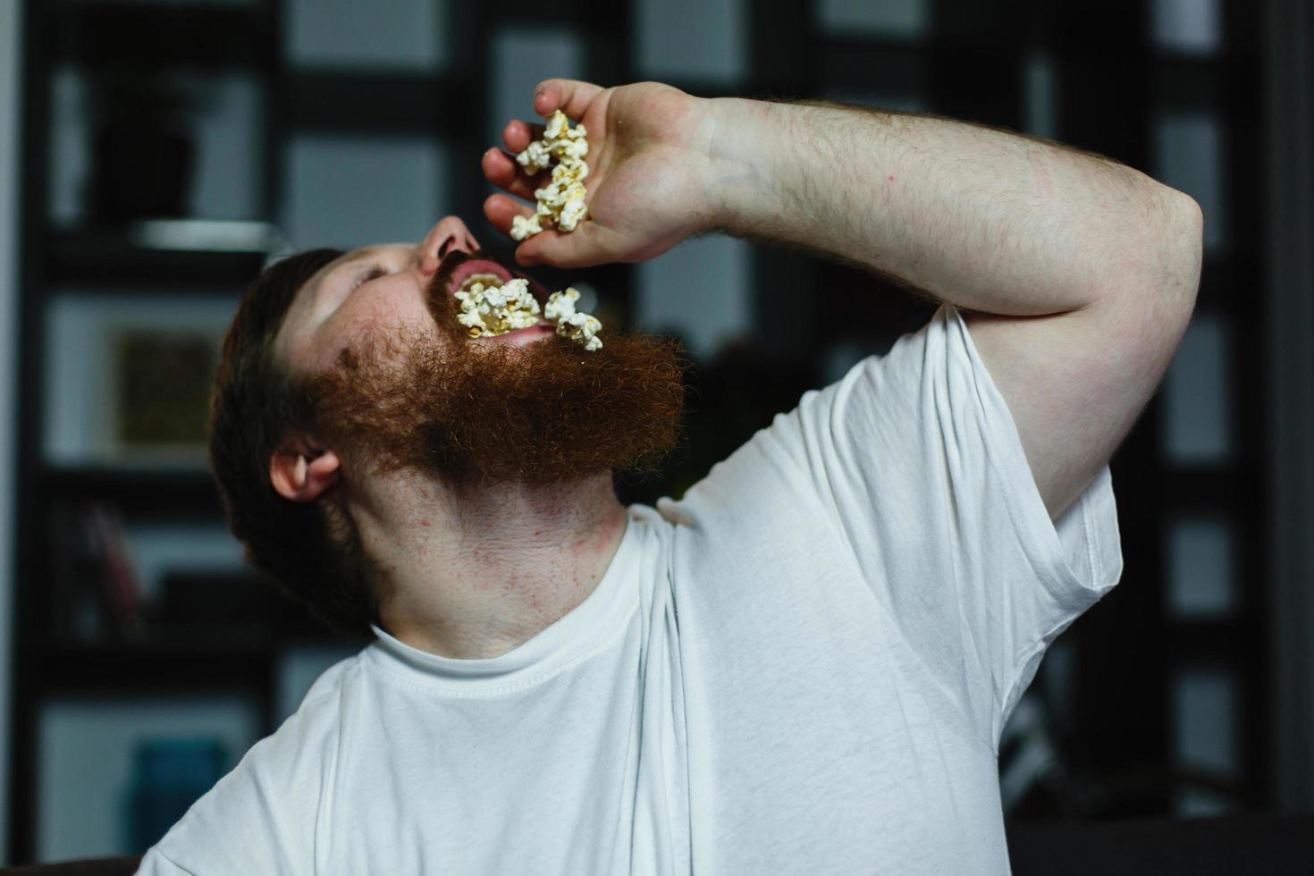 Primer plano de un hombre gordo con aspecto feo mientras come palomitas de maíz foto