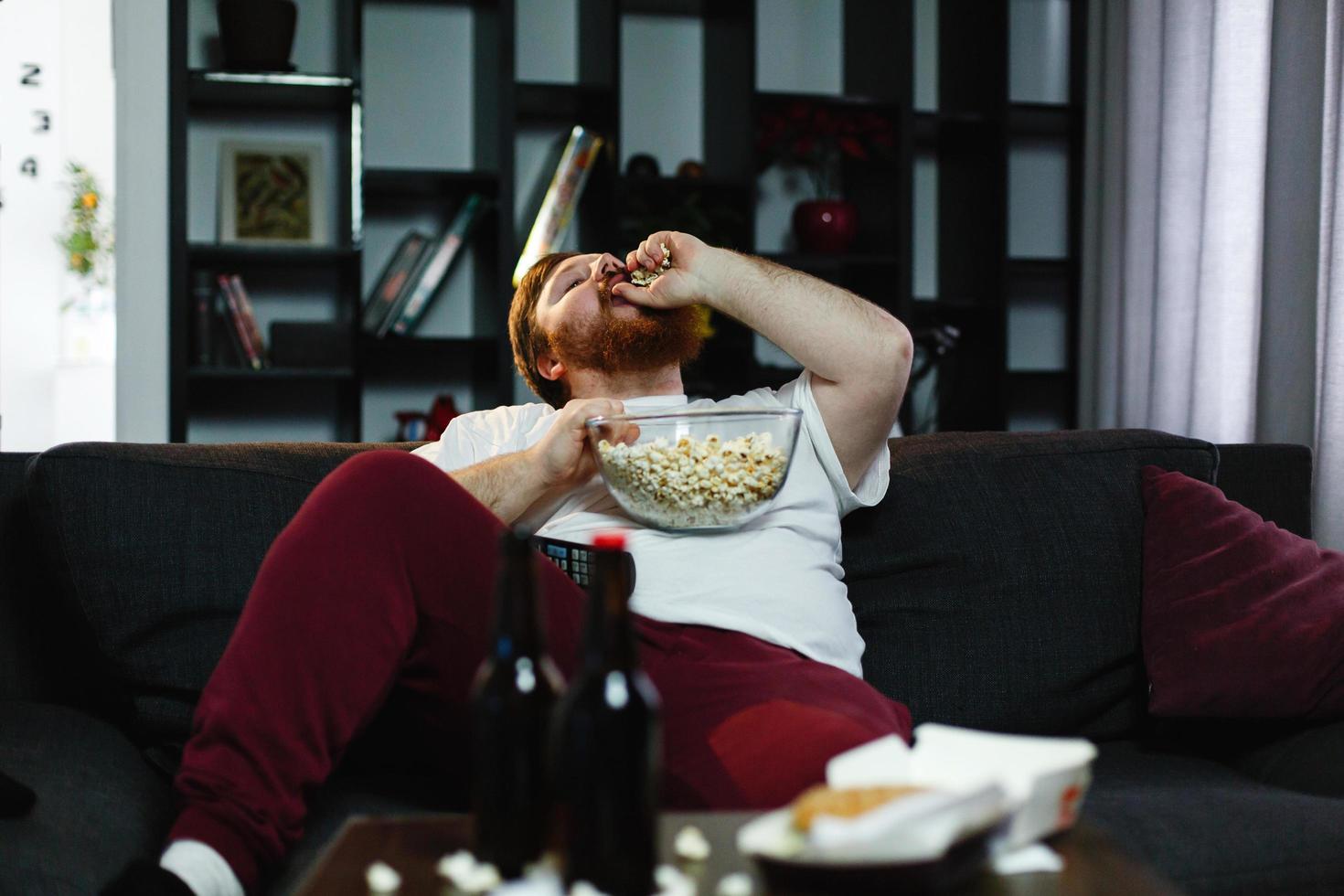 Man eating popcorn on the sofa photo