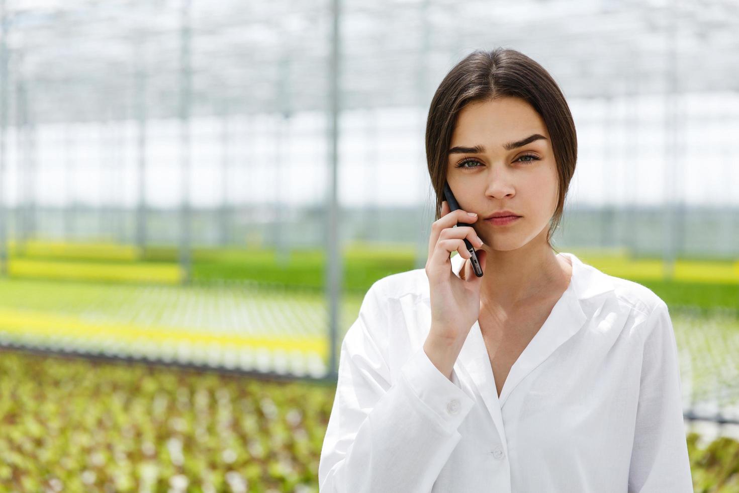 Researcher talks on the phone walking around a greenhouse photo