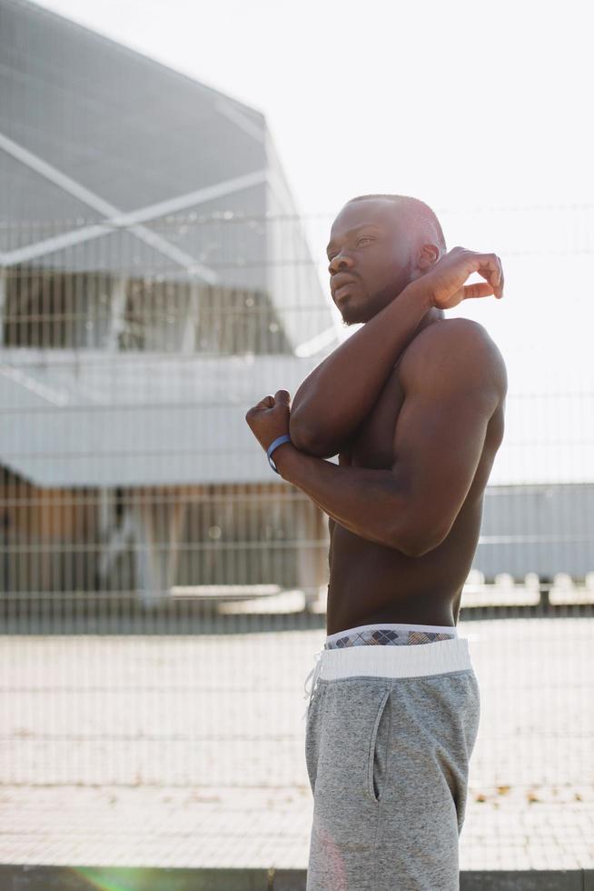 Hombre afroamericano hace estiramientos antes de un entrenamiento foto