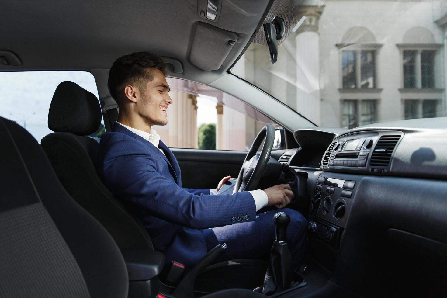 Smiling businessman sits inside the car photo