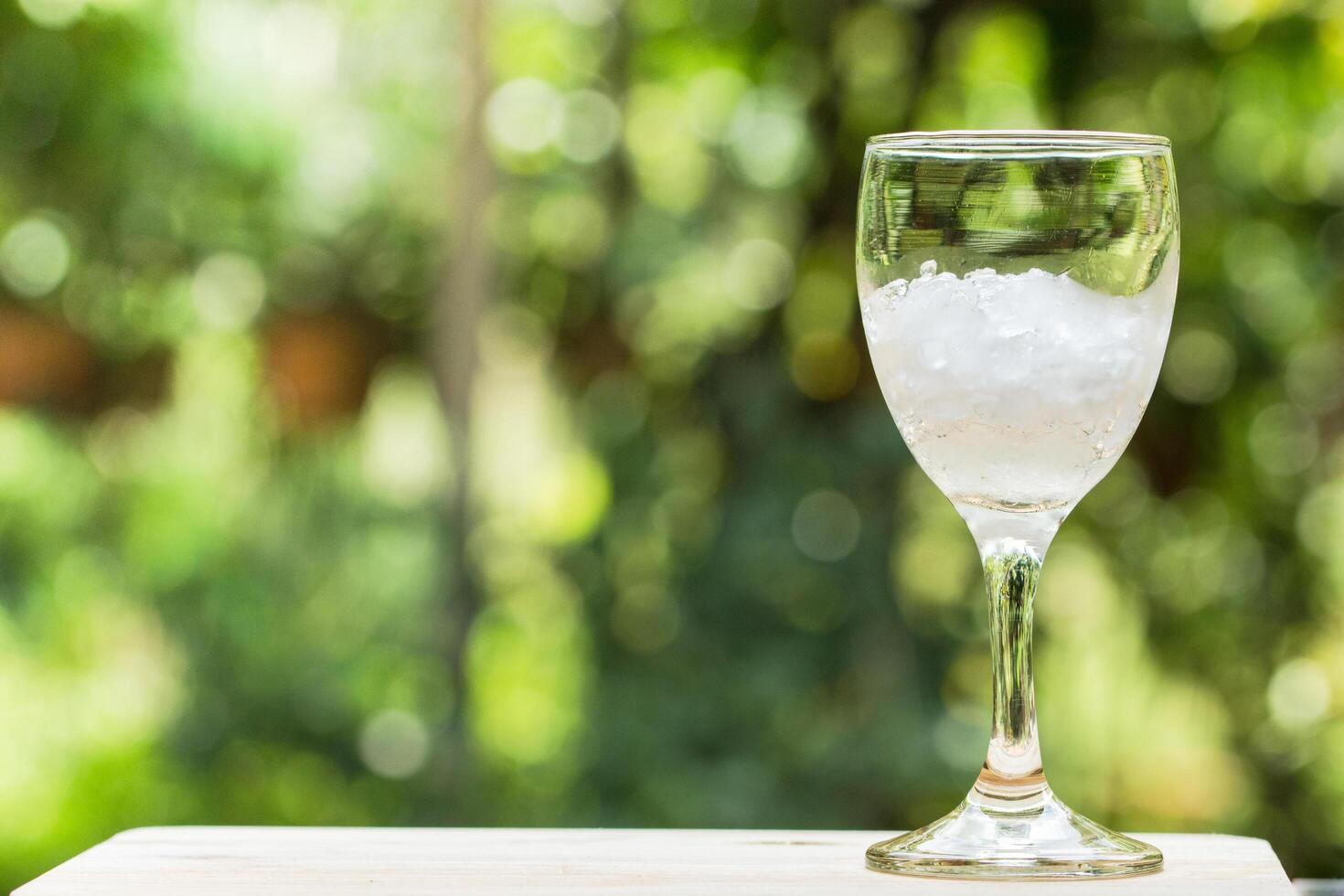 Glass filled with ice on nature background photo