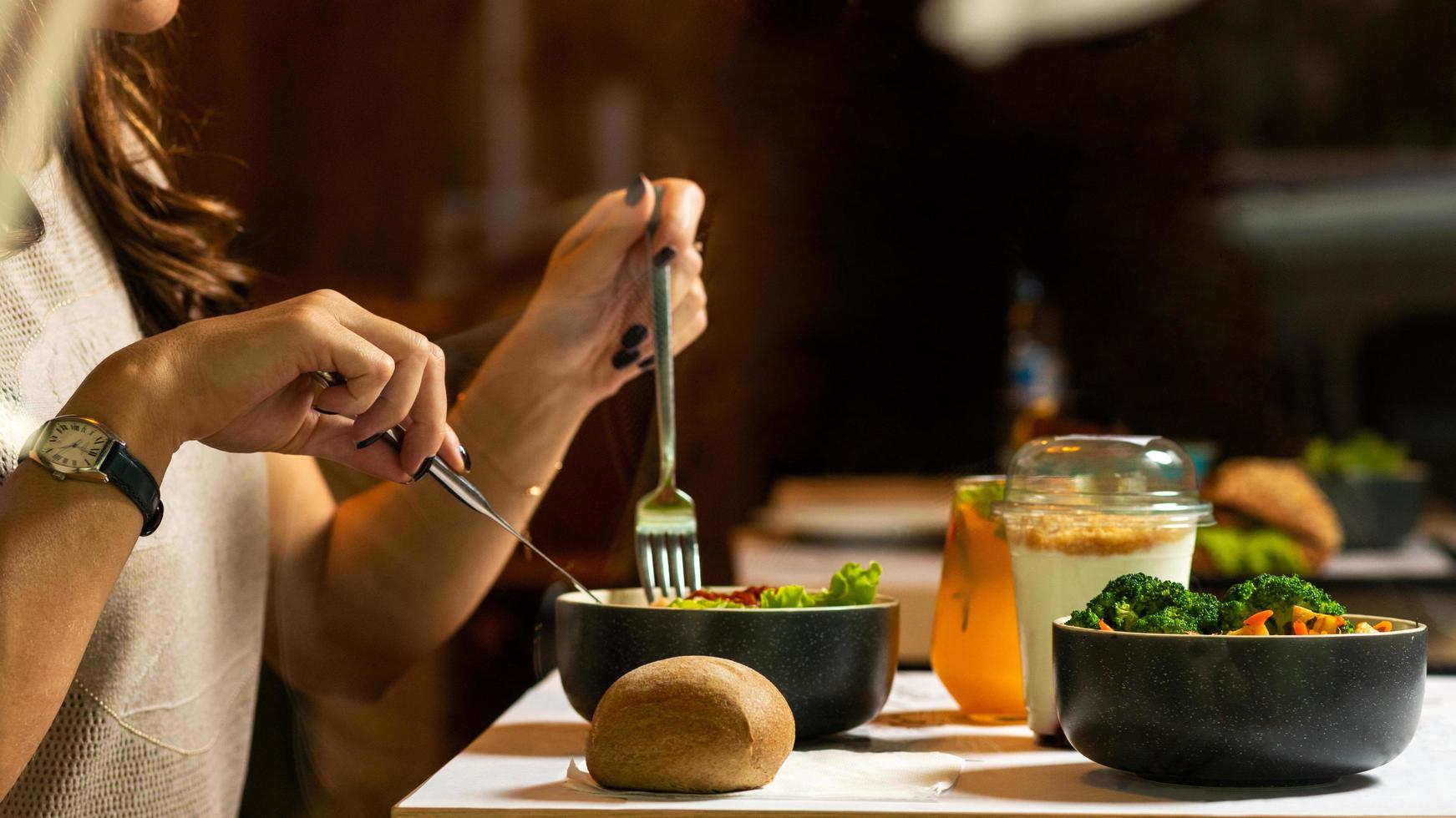 Woman eating tasty chicken salad with dessert photo