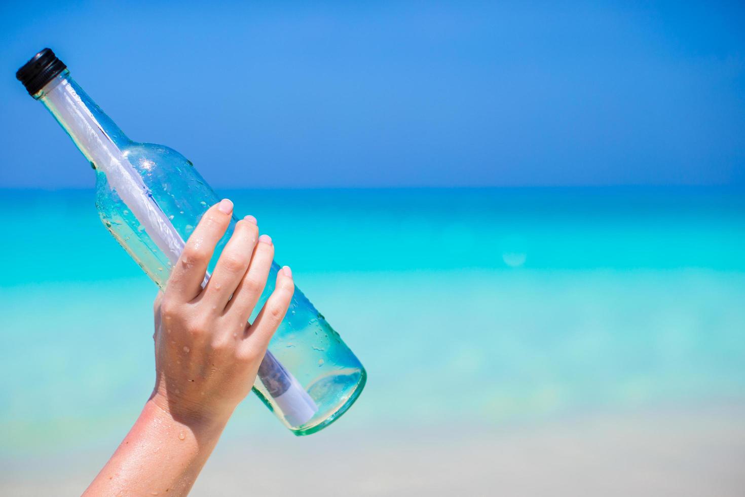 persona sosteniendo un mensaje en una botella foto