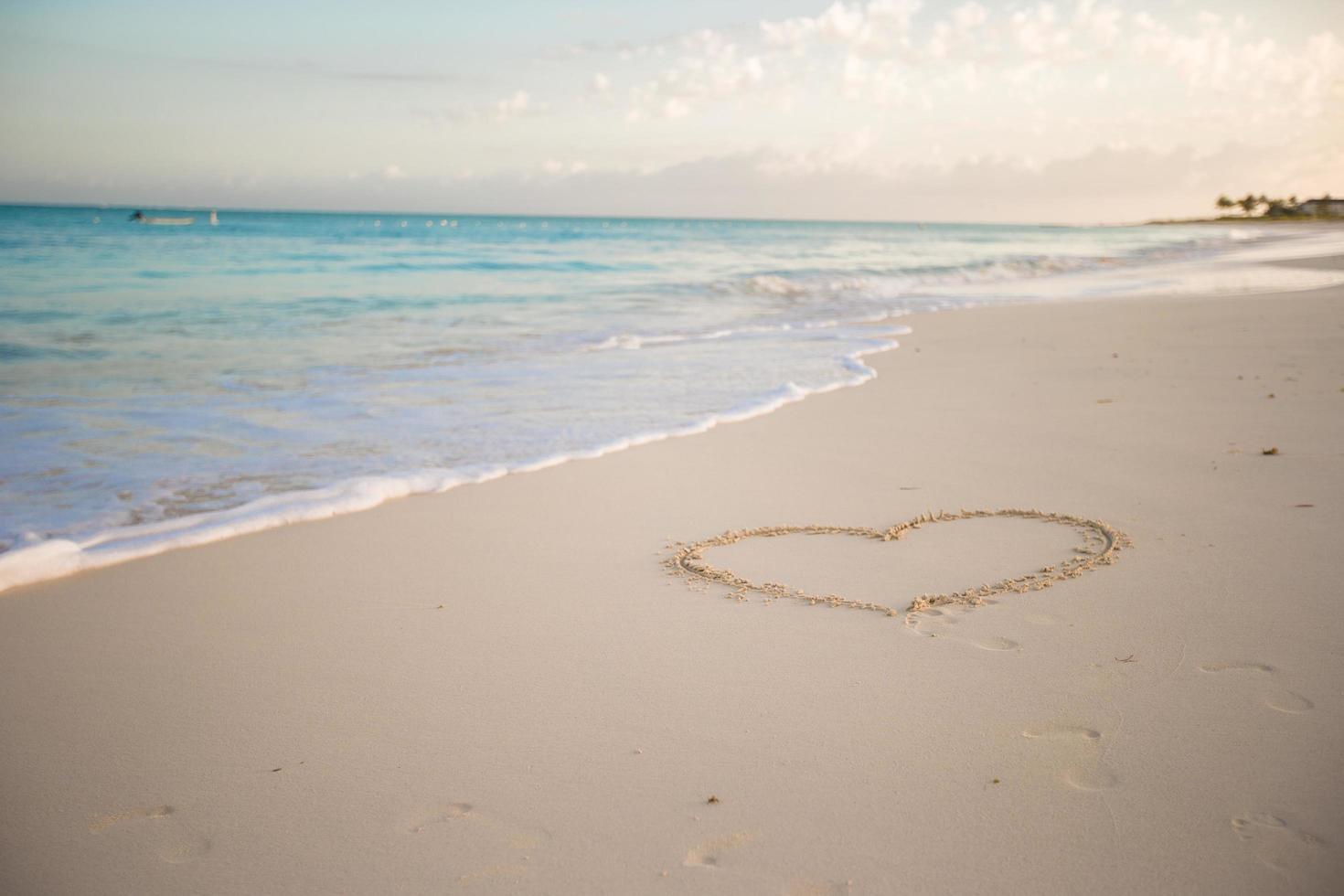 corazón dibujado en la arena de una playa tropical foto