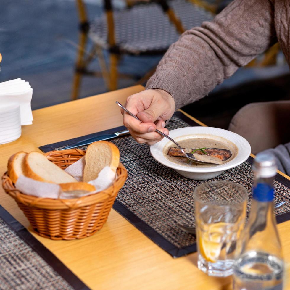 persona comiendo sopa de champiñones foto