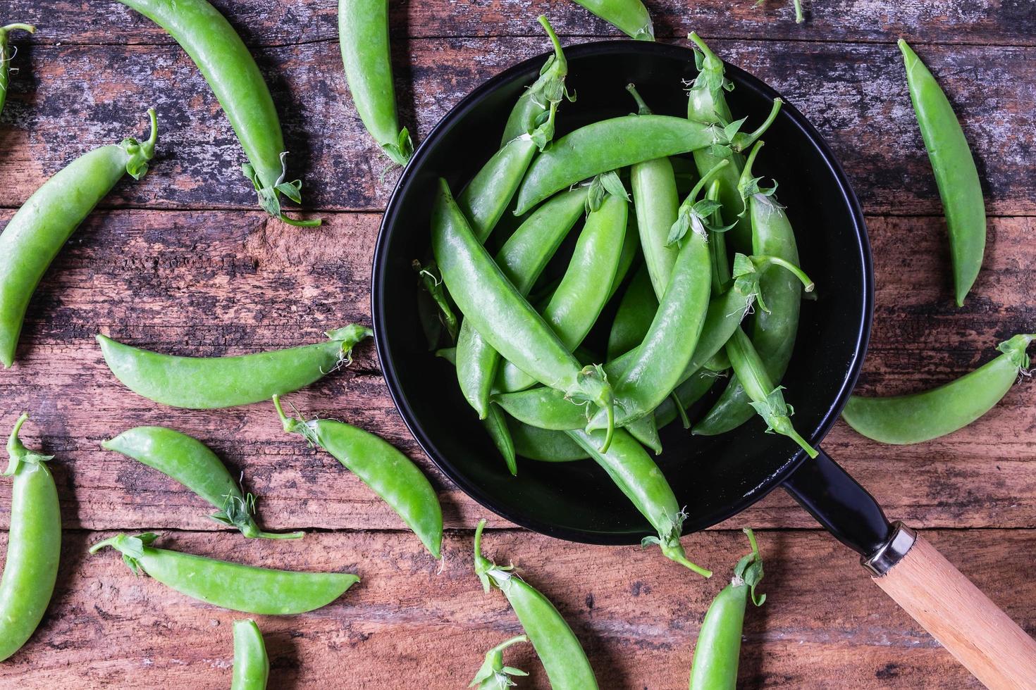 guisantes verdes frescos en la sartén sobre la mesa de la cocina foto