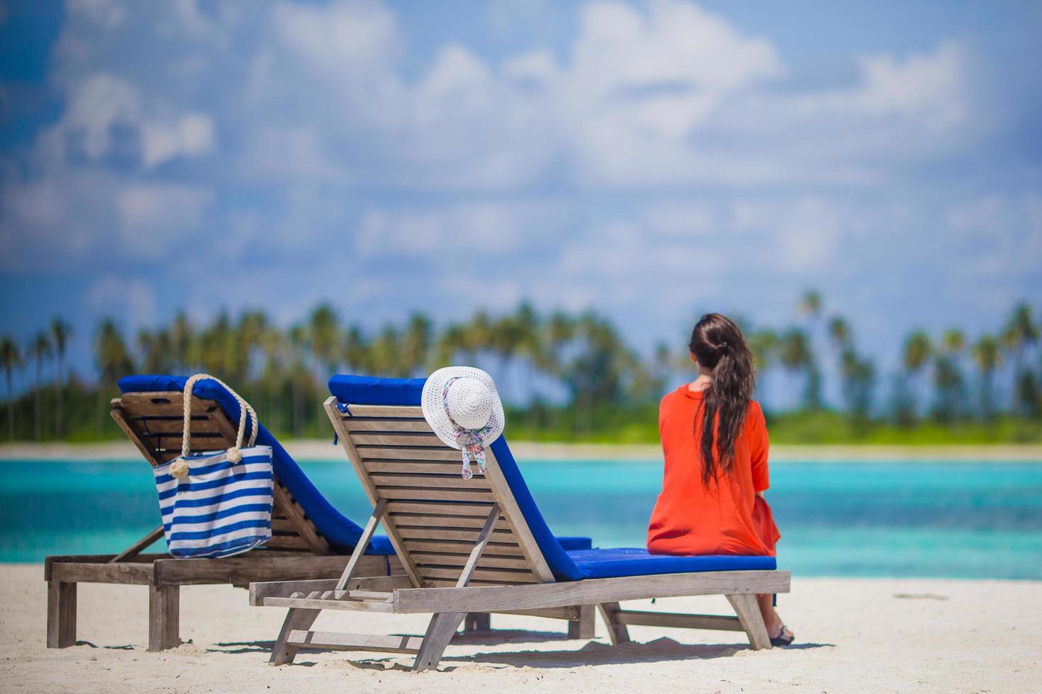 Woman sitting on  a  lounge chair on a  beach photo
