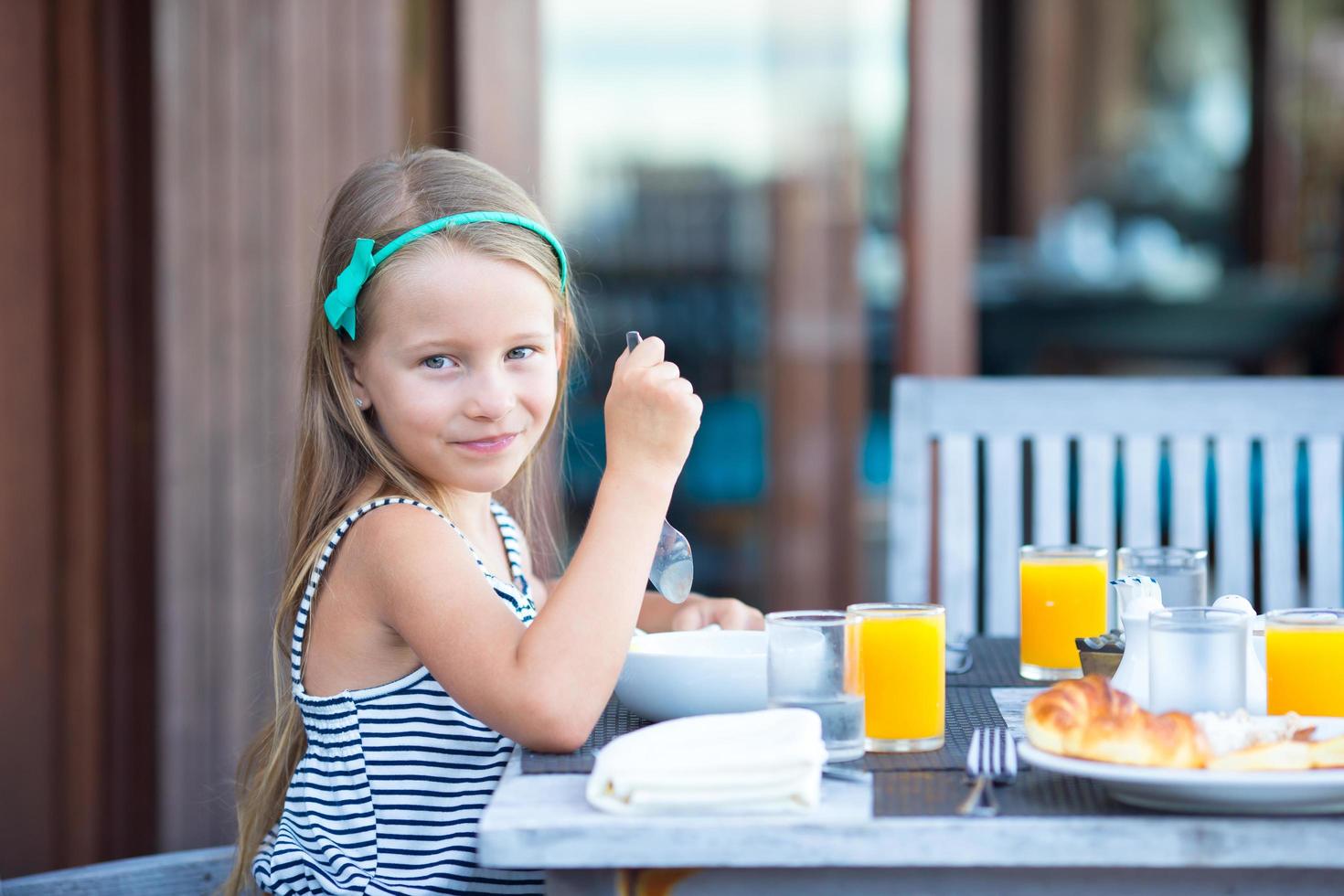 niña sonriendo a la mesa del desayuno foto