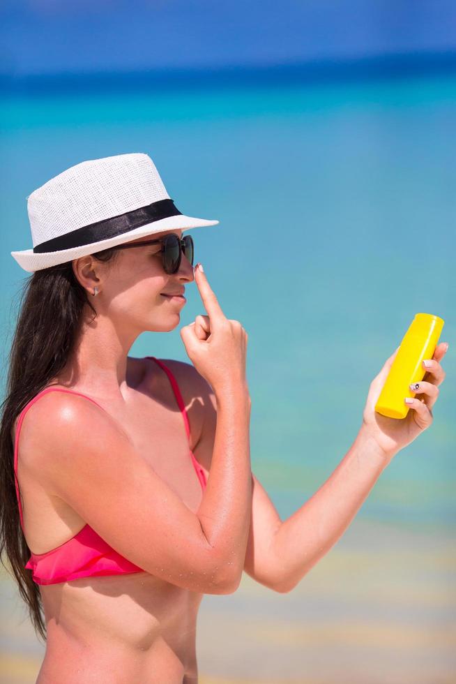 Mujer aplicando protector solar en la playa foto